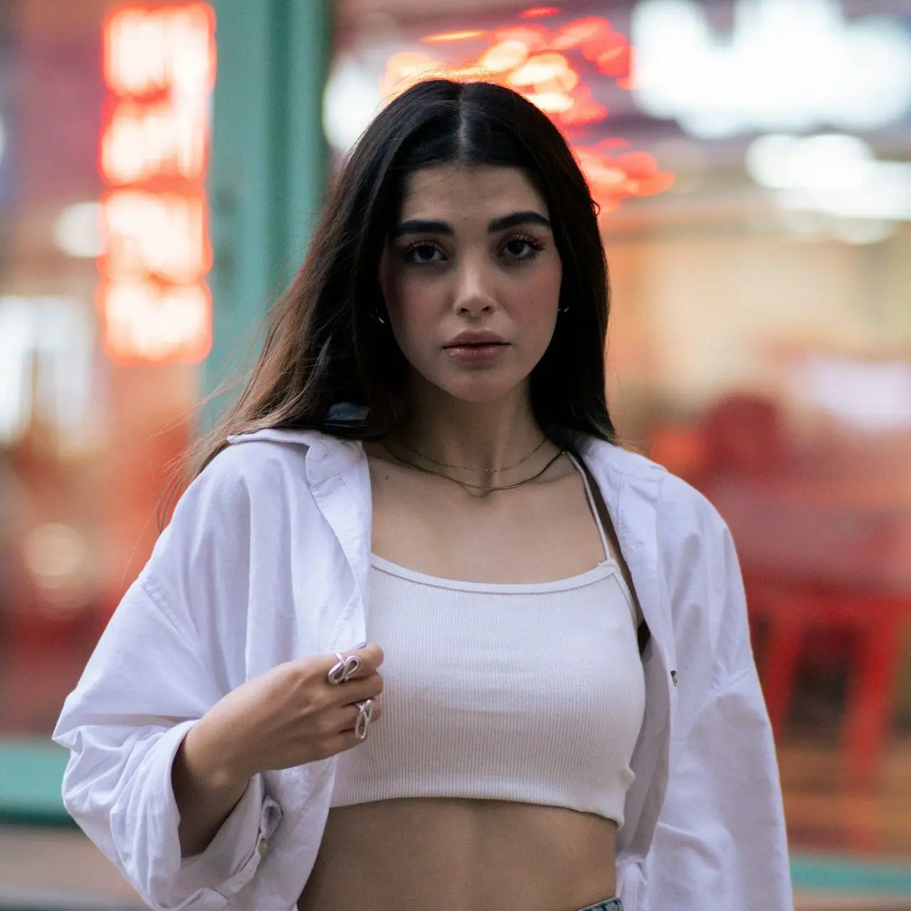 Woman poses wearing a white shirt and jeans.